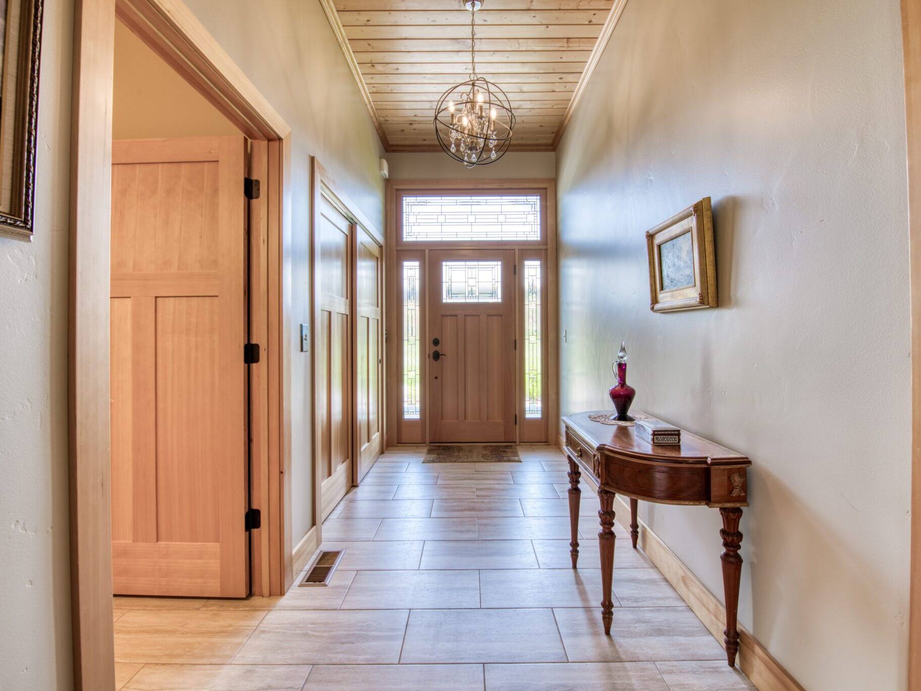 Entry foyer with tile floors, wood ceiling, trim and doors in a custom home by Big Sky Builders in Hamilton, MT.