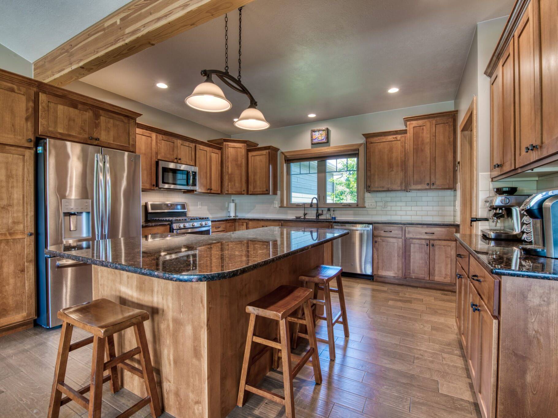 Kitchen with hardwood flooring, wood cabinetry, granite countertops, and tiled backsplash in a custom home in Hamilton, MT