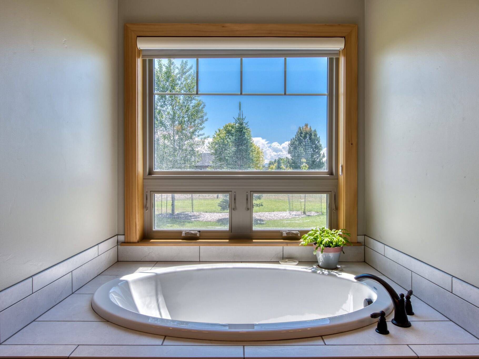 Soaking tub in a tiled tub deck with a large window in a custom home near Hamilton, MT.