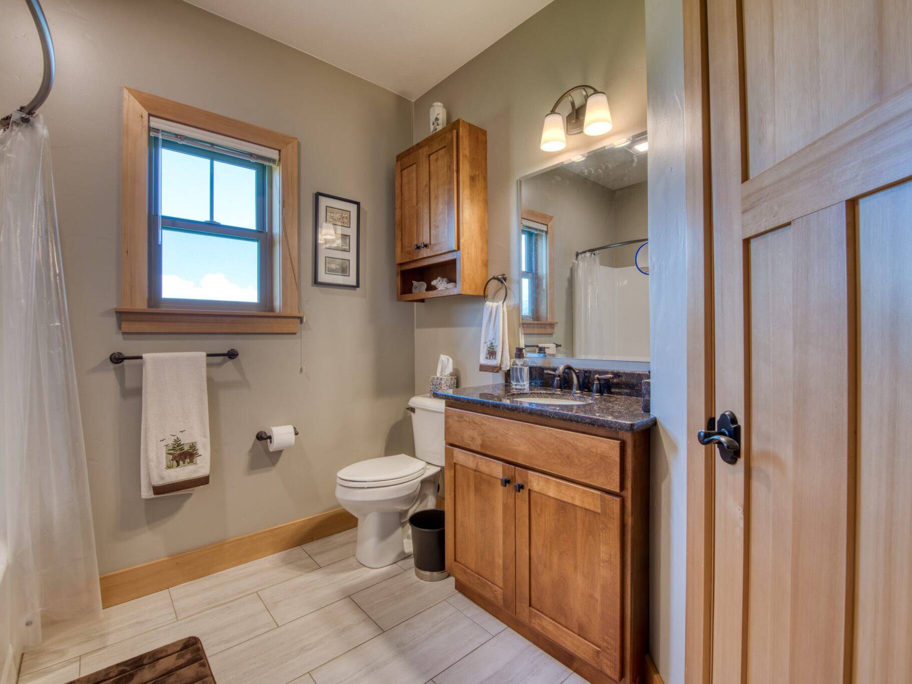 Guest bathroom with tile floor, granite countertops, and wood trim in a custom home in Hamilton, MT.
