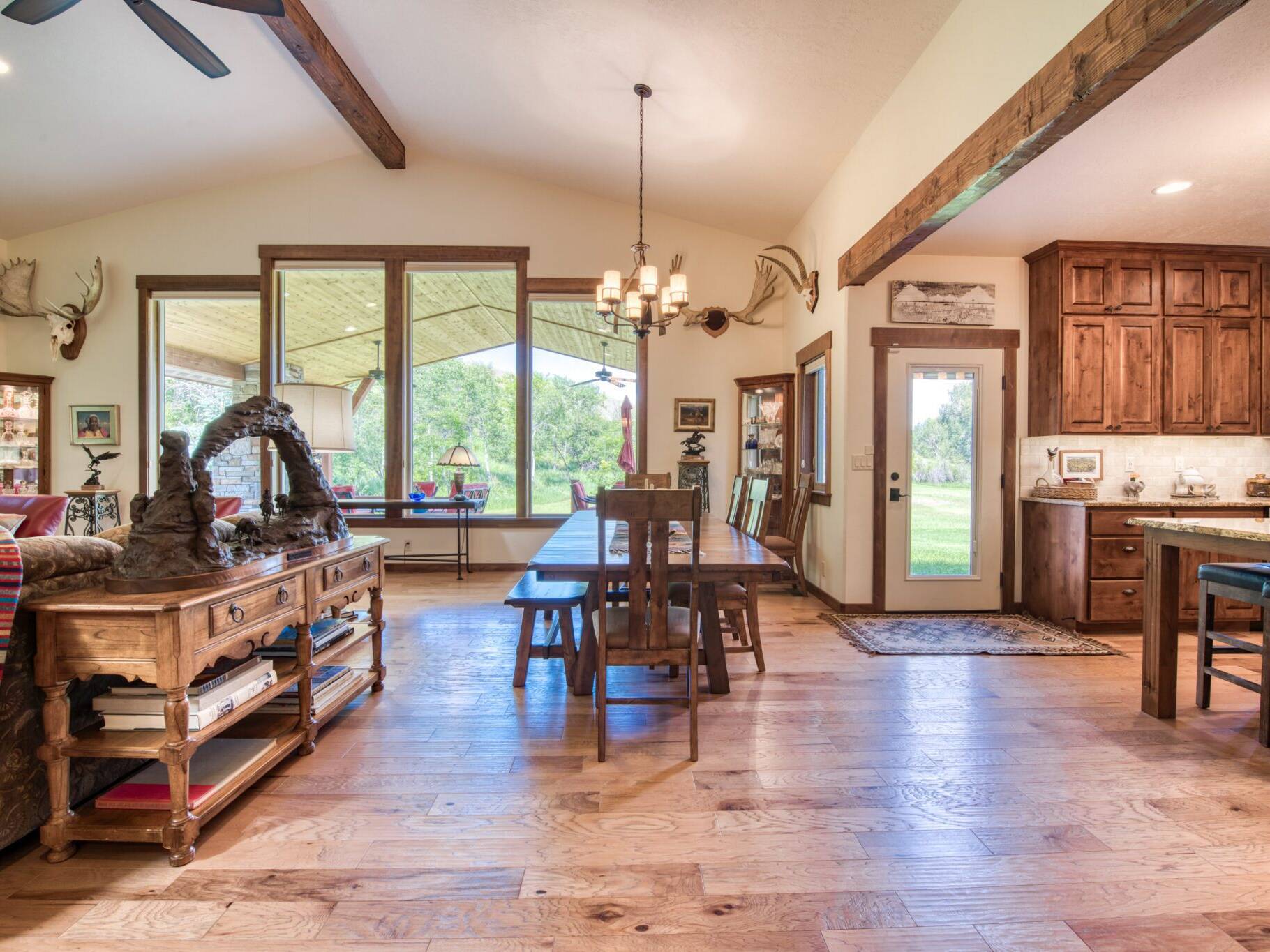Dining room with hardwood floors, large windows, vaulted ceiling with accent beam in a custom home near Hamilton, MT