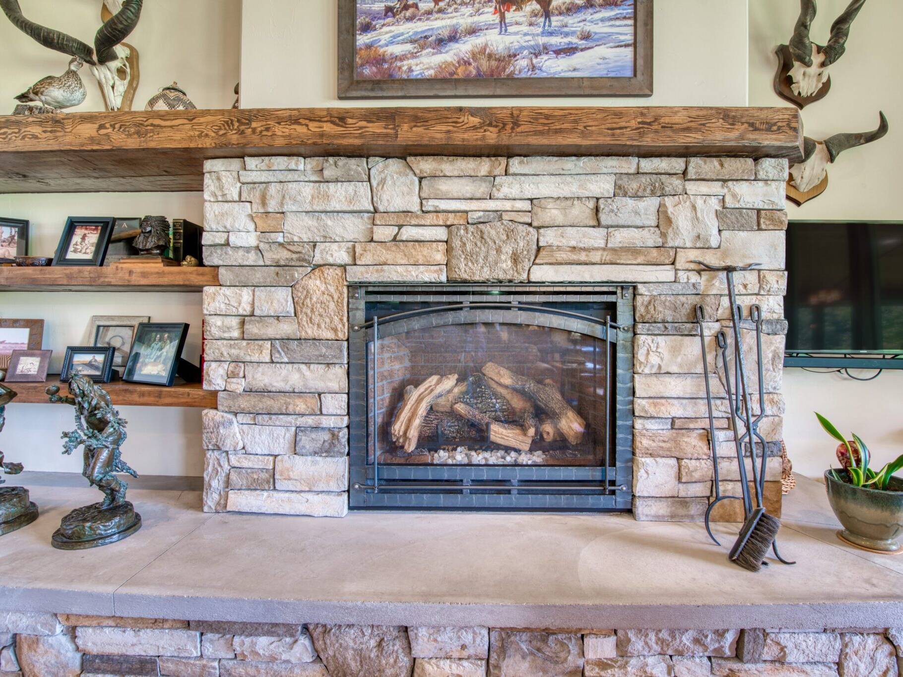 Custom gas fireplace, with stone surround, raised hearth, and stained wood mantle in a custom home near Hamilton, MT