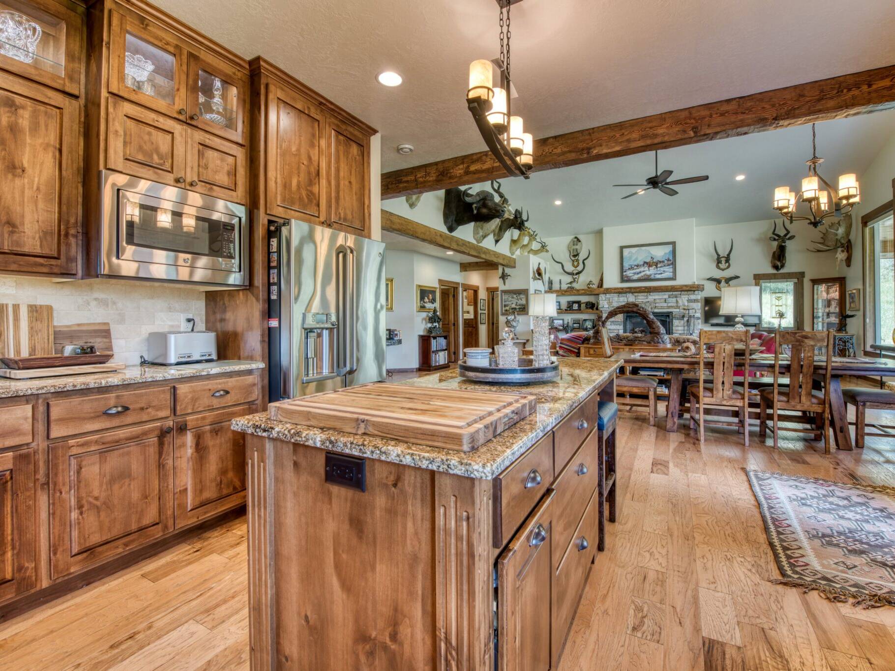 Kitchen with an island, rustic stained wood cabinets, granite countertops, tile backsplash in a custom home near Hamilton, MT