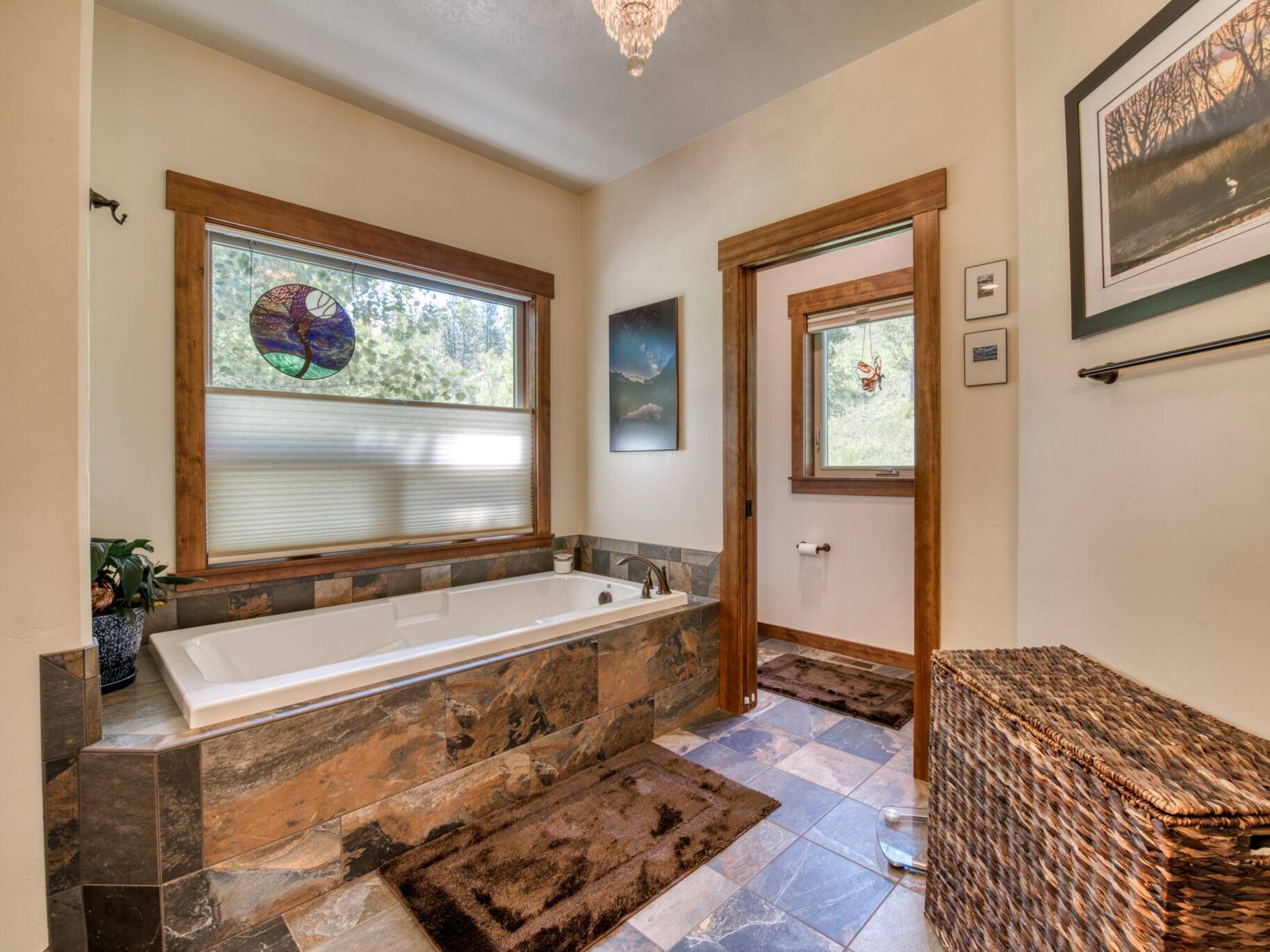 Master bathroom with tile floors, a soaking tub set in a tiled tub deck with a large window in a custom home near Hamilton, MT