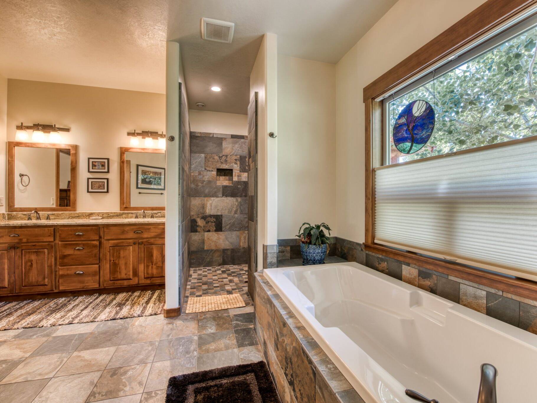 Master bathroom with tile floors, tile shower, granite countertops, soaking tub set in a tiled tub deck with a large window in a custom home near Hamilton, MT