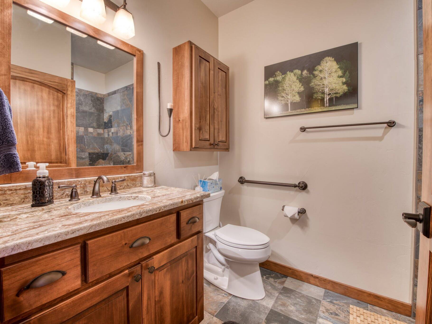 Guest bathroom with tile floors, granite countertops, and wood cabinetry & trim in a custom home near Hamilton, MT