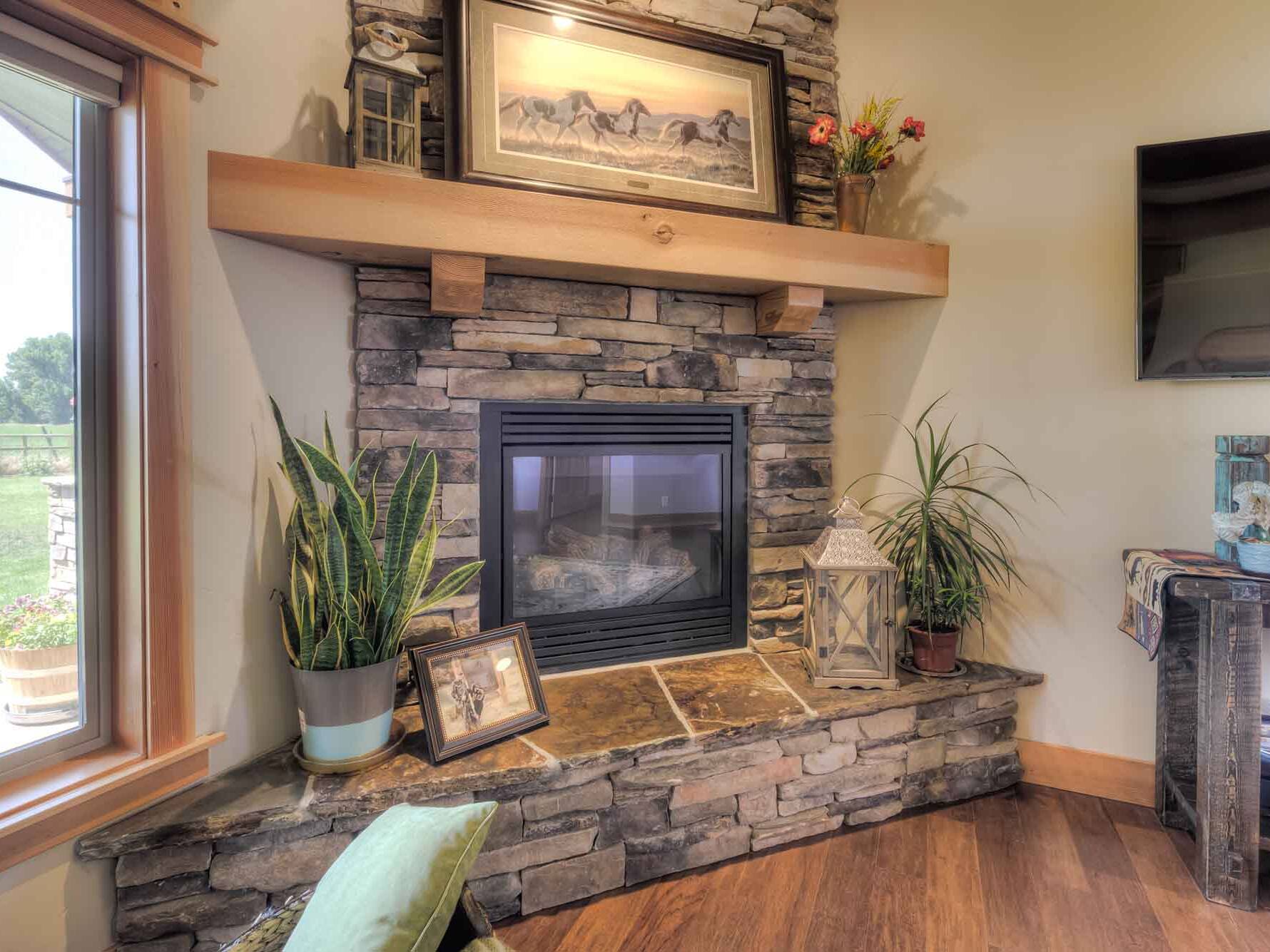 Corner fireplace with cultured stone and wood mantle inside a custom home built by Big Sky Builders in Hamilton, Montana