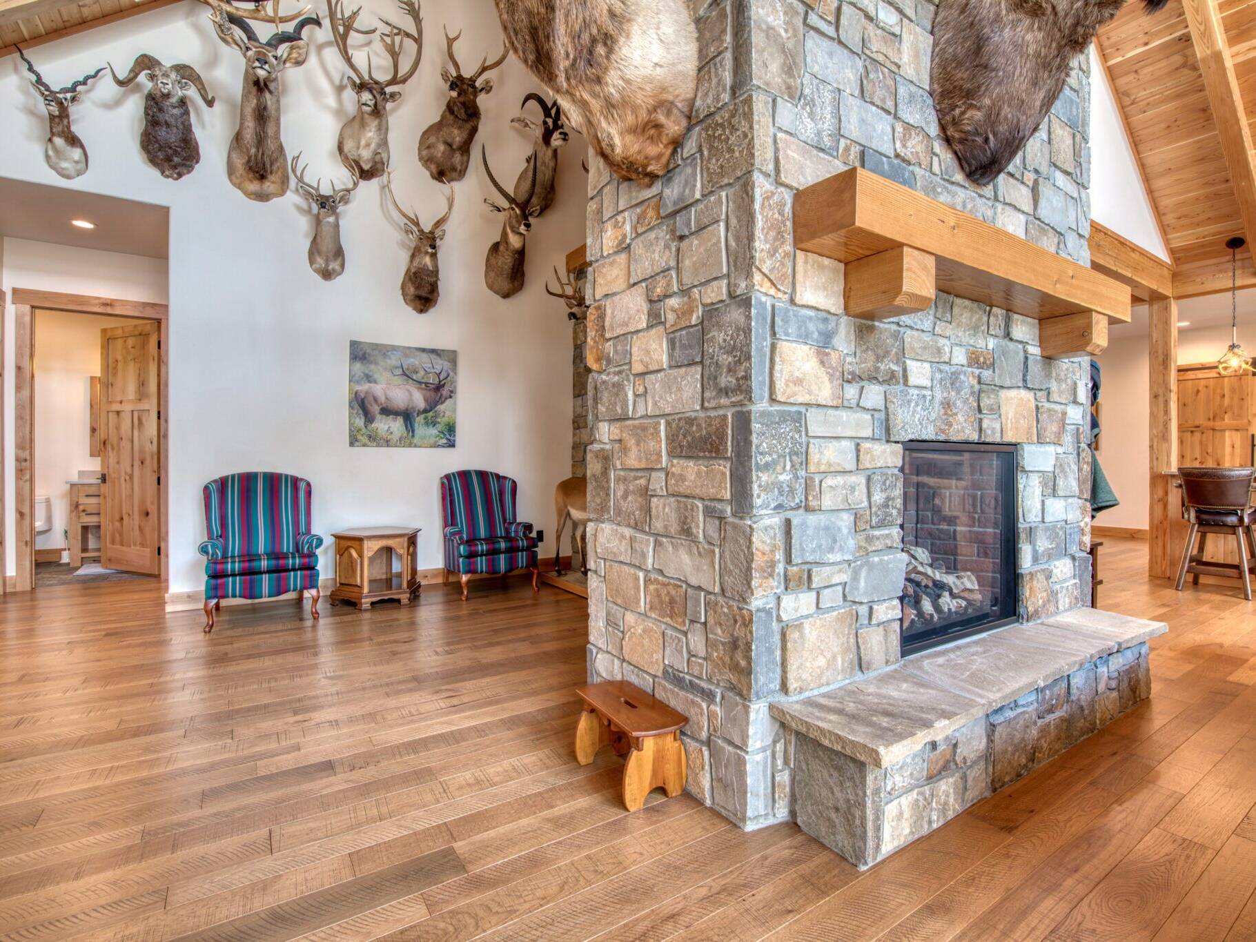 Great room with large fireplace, wood floors, vault ceiling with pine T&G and wood beams in a custom home built by Big Sky Builders of Monana in Florence, MT