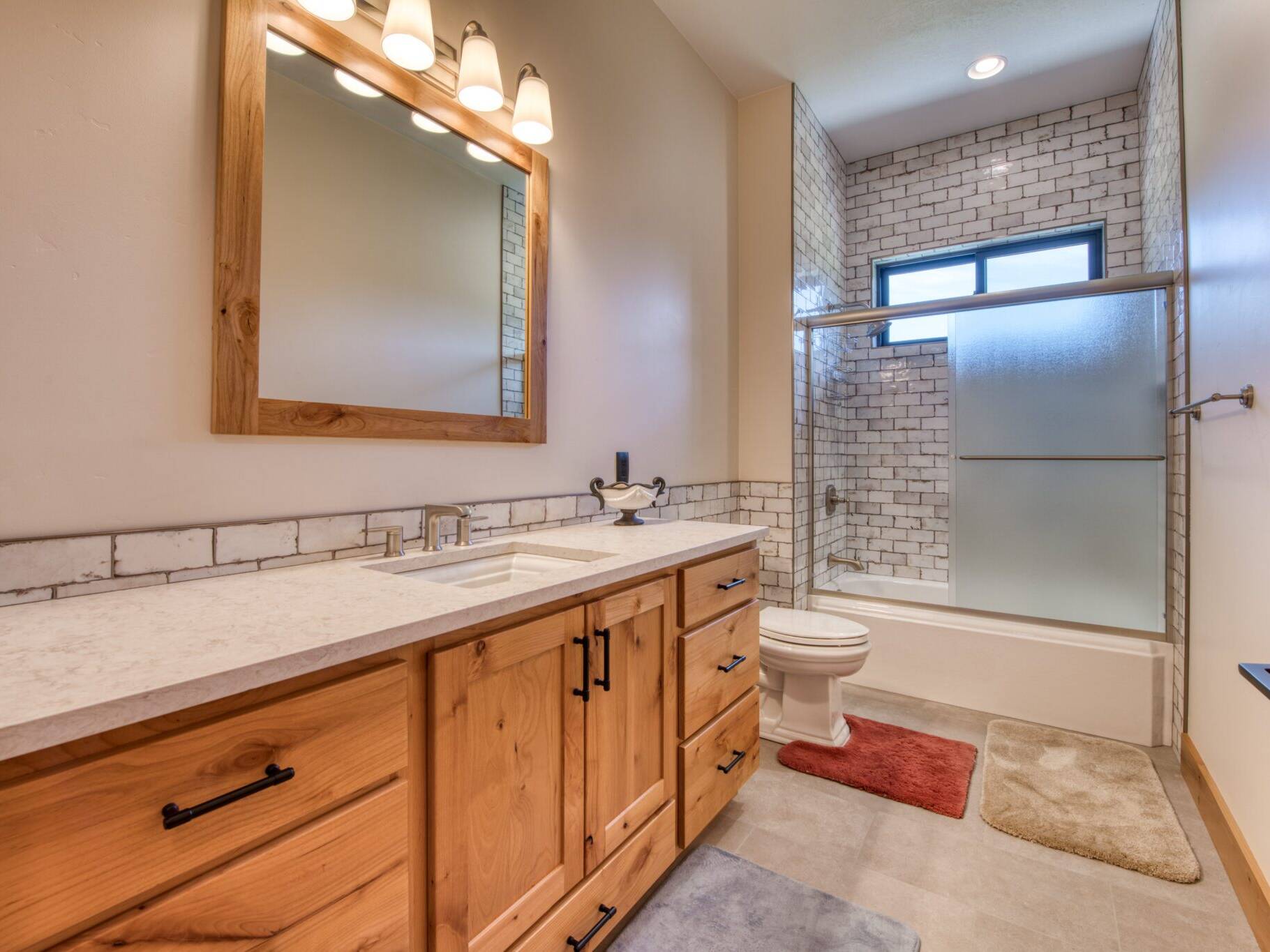 Bathroom with alder cabinets, granite countertop, tile floors and tile tub-shower surround in a custom home built by Big Sky Builders of Montana in Florence, MT