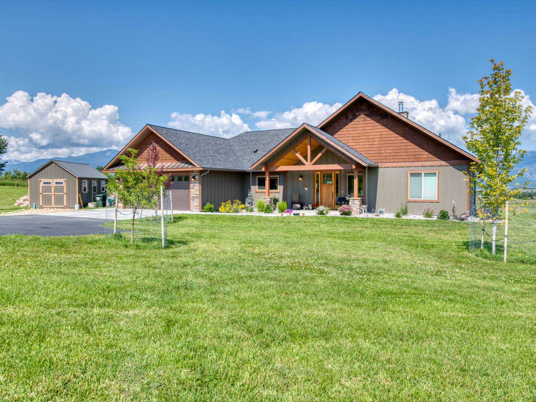 Front exterior, featuring a timber truss at the entry and a copper roof accent over the garage on a custom home built by Big Sky Builders in Stevensville, MT