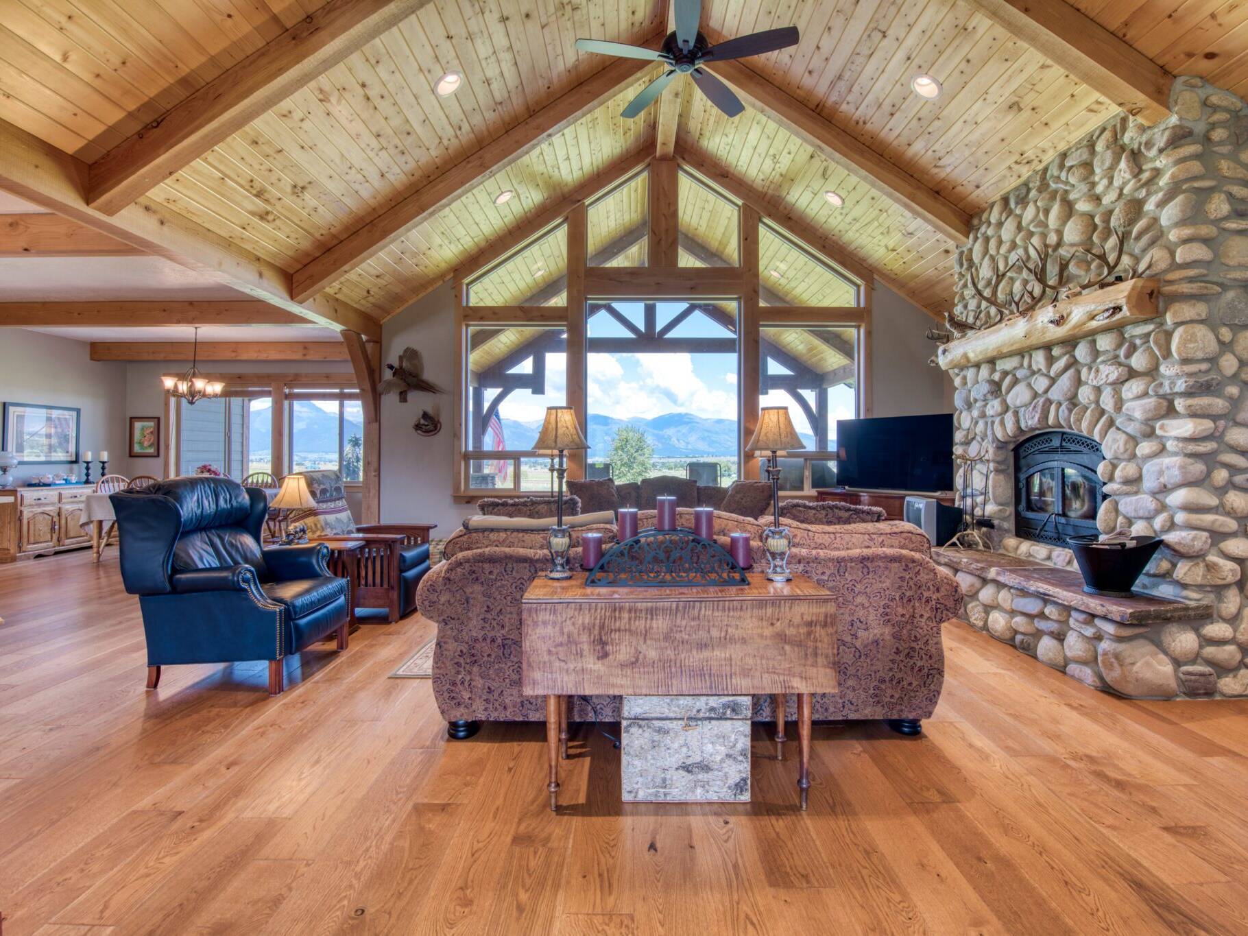 Great room custom wood burning fireplace with natural river rock, vaulted T&G ceiling with wood beams in a custom home built by Big Sky Builders in Stevensville, MT