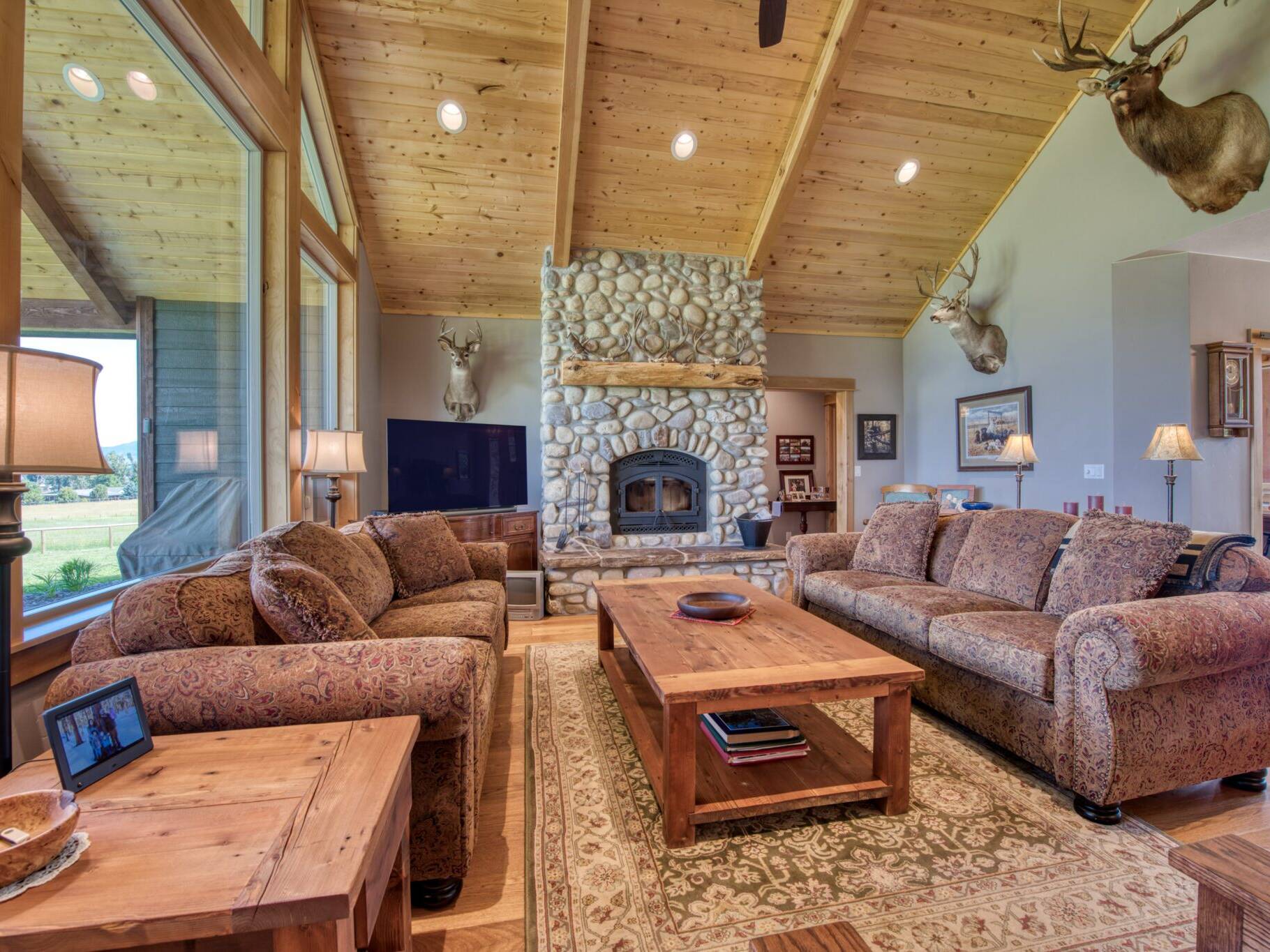 Great room custom wood burning fireplace with natural river rock, vaulted t&g ceiling with wood beams in a custom home built by Big Sky Builders in Stevensville, MT