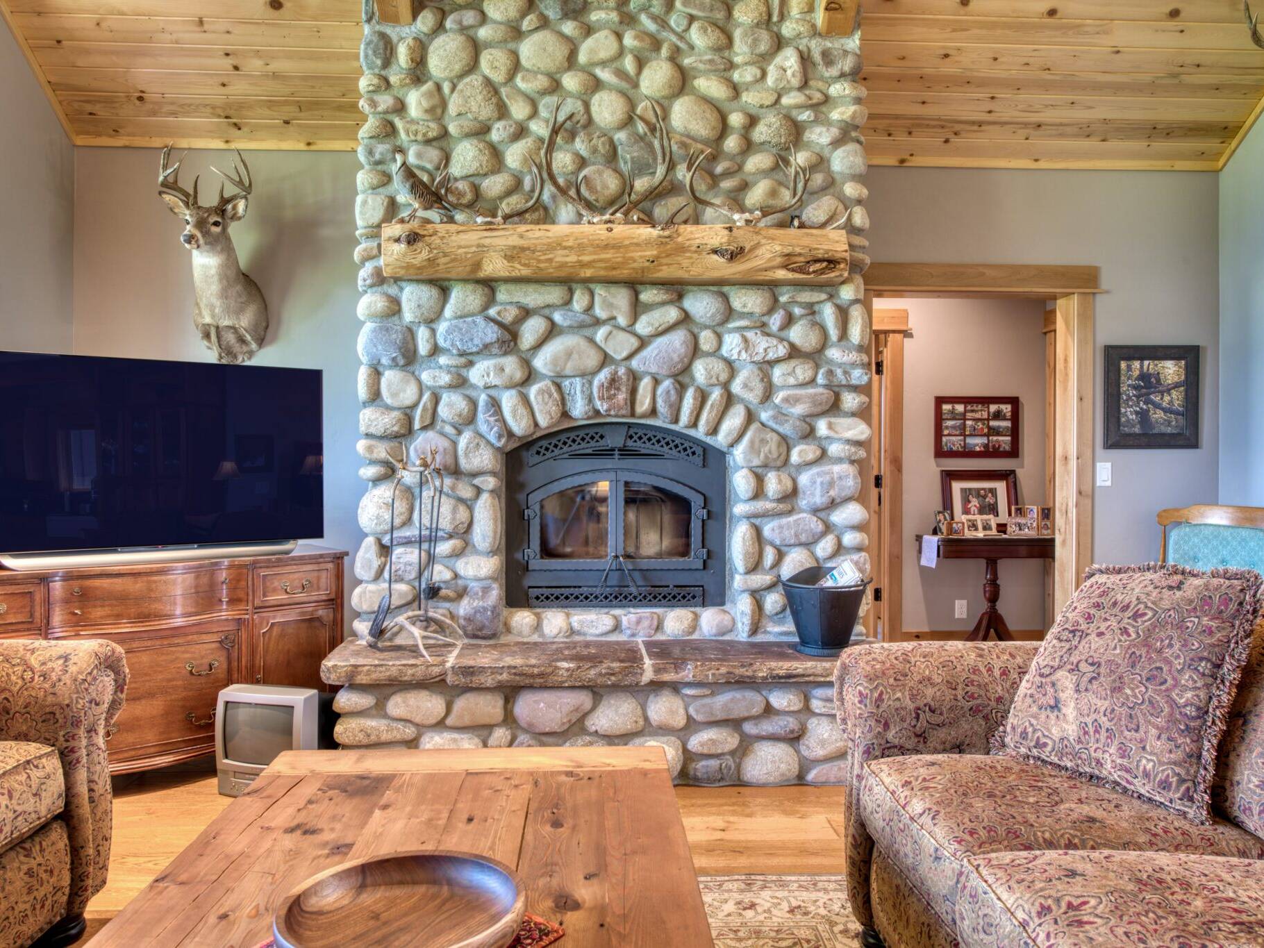 Great room custom wood burning fireplace with natural river rock and a raised hearth in a custom home built by Big Sky Builders in Stevensville, MT