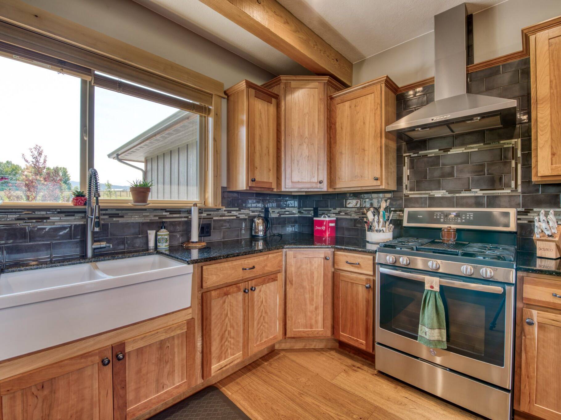 Kitchen farm sink & gas range with tile backsplash in a custom home built by Big Sky Builders in Stevensville, MT