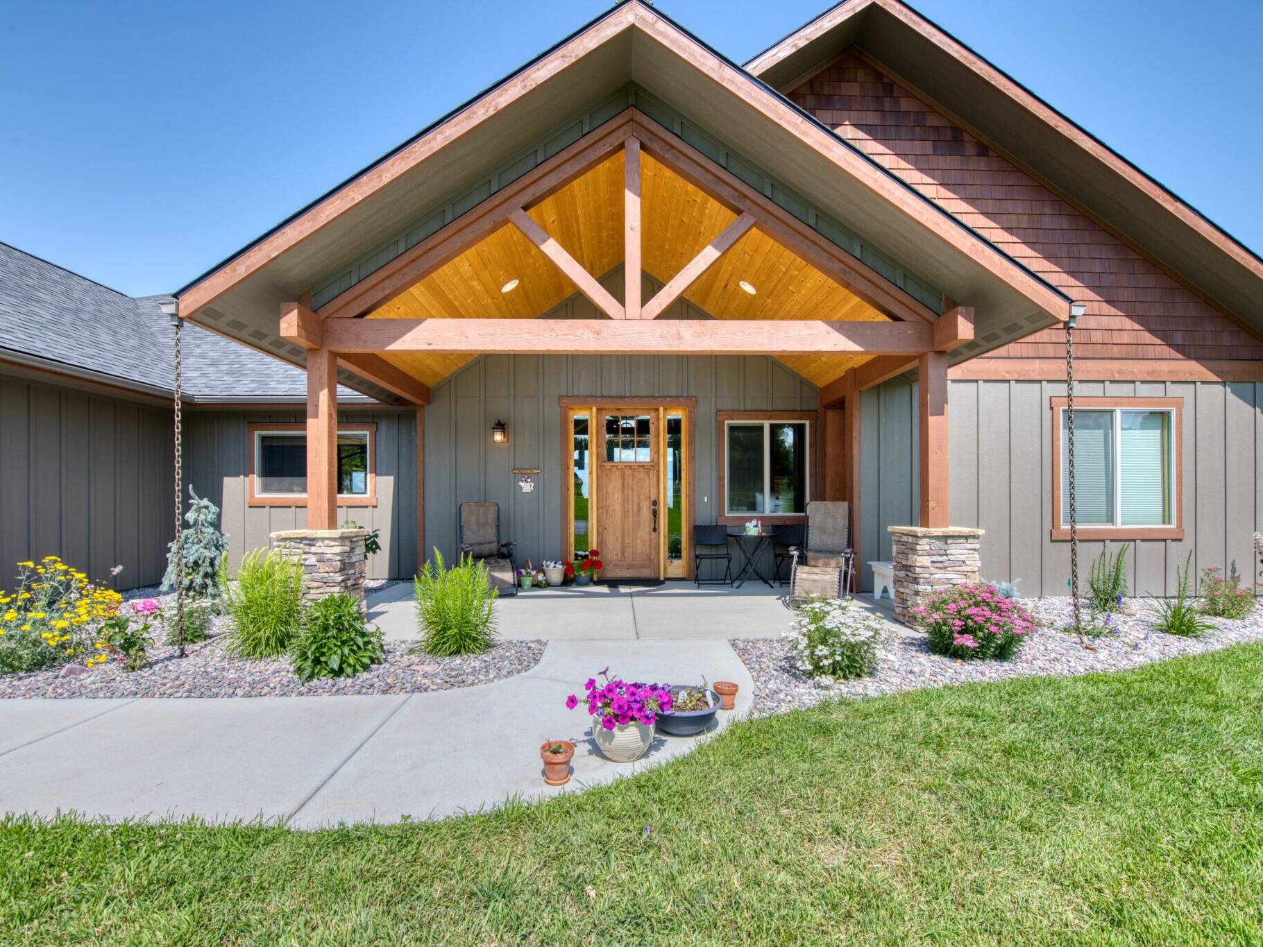 Covered front porch with vaulted T&G pine ceiling and timber truss at a custom home built by Big Sky Builders in Stevensville, MT