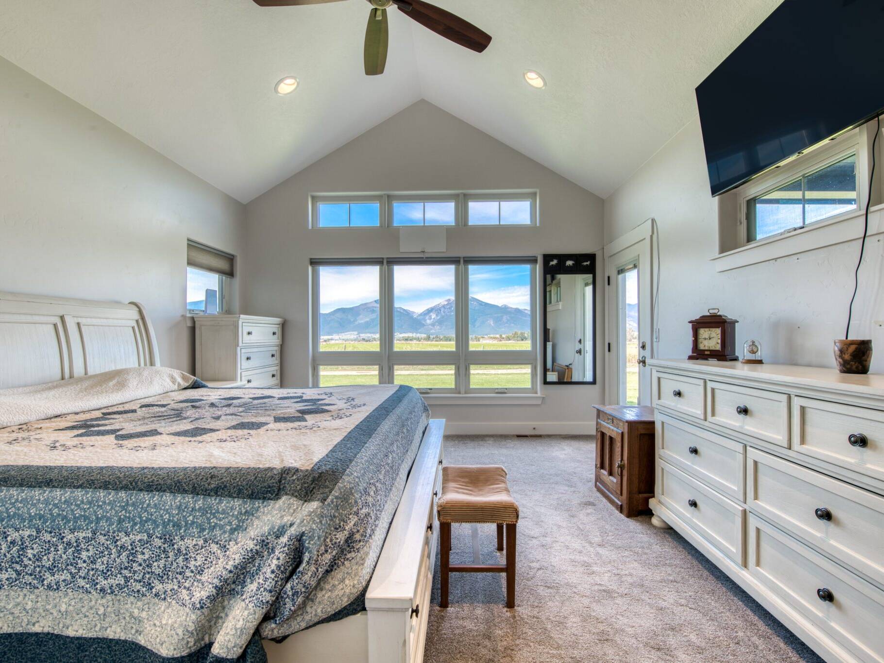 Master bedroom with a vaulted ceiling, carpet floors, and large windows in a custom home built by Big Sky Builders in Stevensville, MT