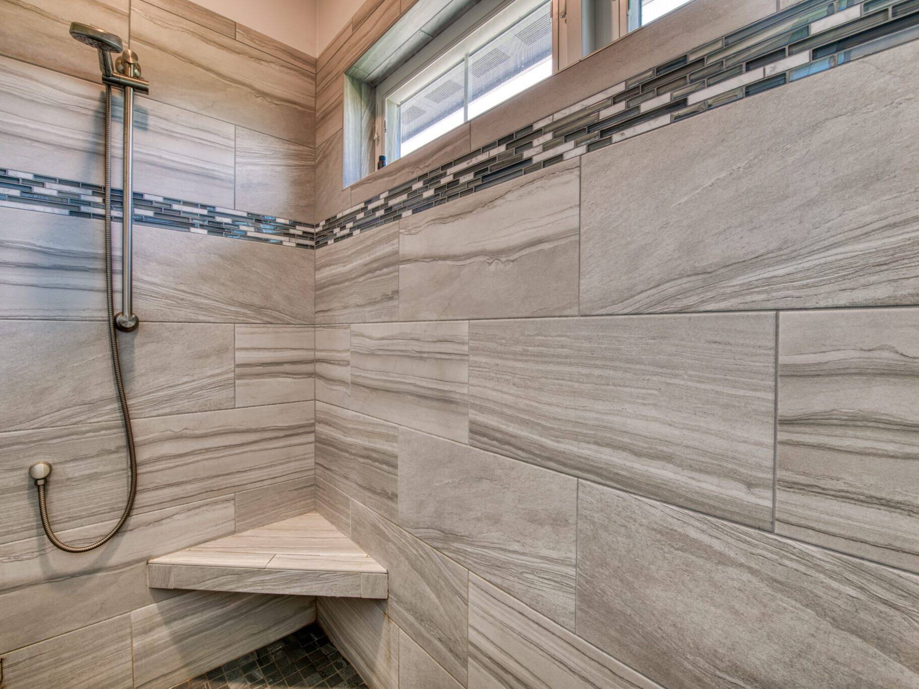 Master shower with tile walls, a corner seat and windows in a custom home built by Big Sky Builders in Stevensville, MT