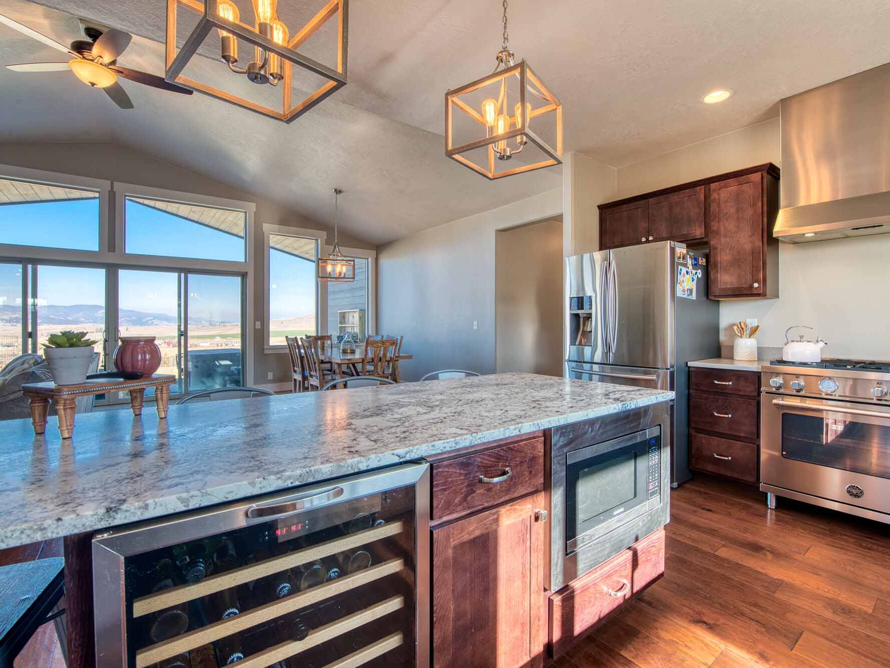 Kitchen with island, granite countertops and wood floors in The Copper Creek model home - Built by Big Sky Builder in Florence, MT