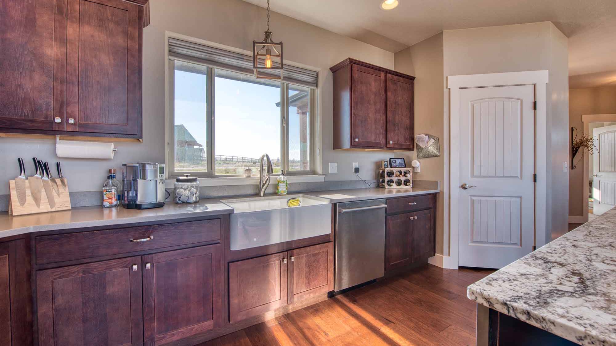 Kitchen with island, granite countertops and wood floors in The Copper Creek model home - Built by Big Sky Builder in Florence, MT