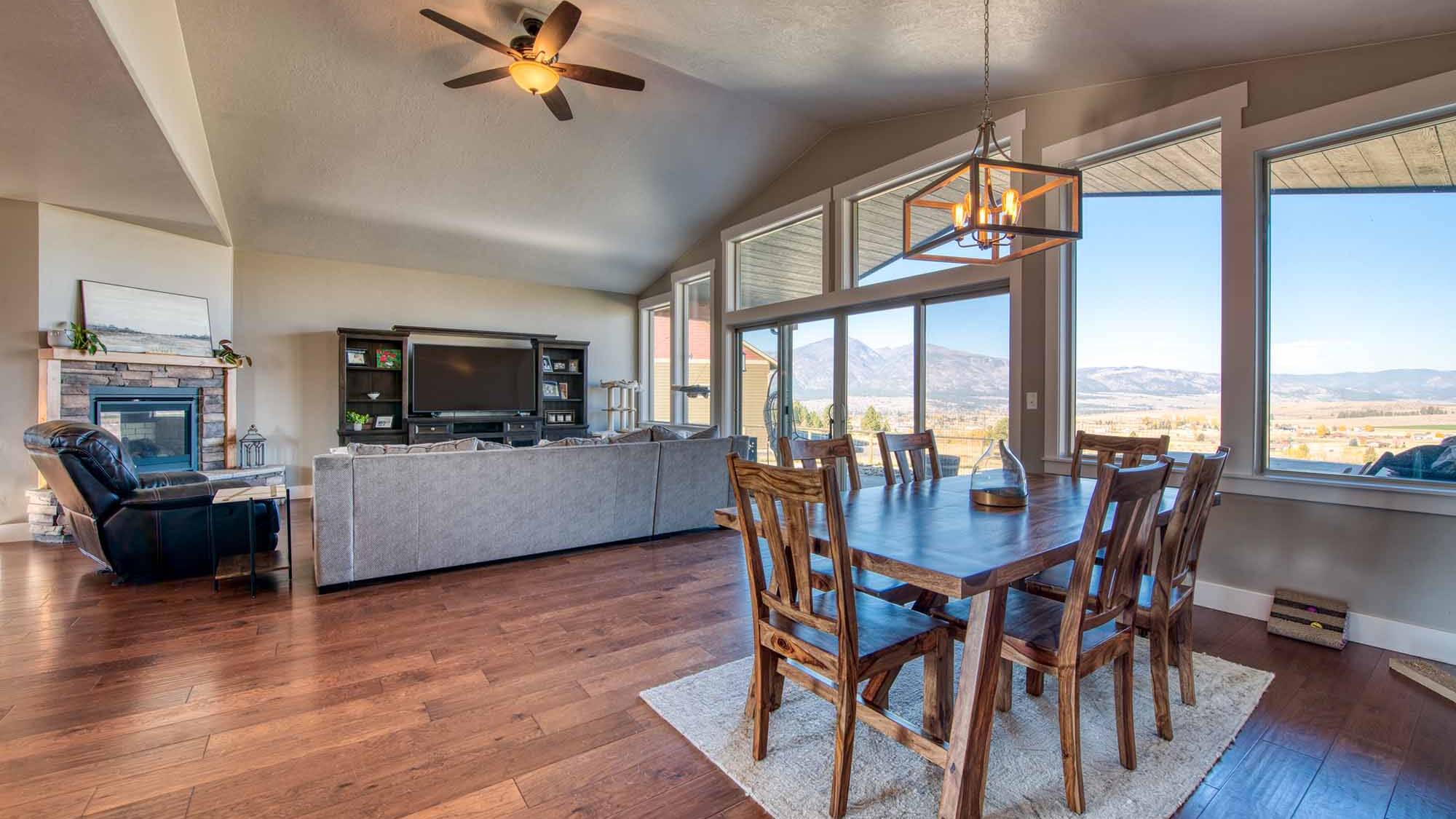 Dining area & living room with vaulted ceiling and wood floors in The Copper Creek model home - Built by Big Sky Builder in Florence, MT