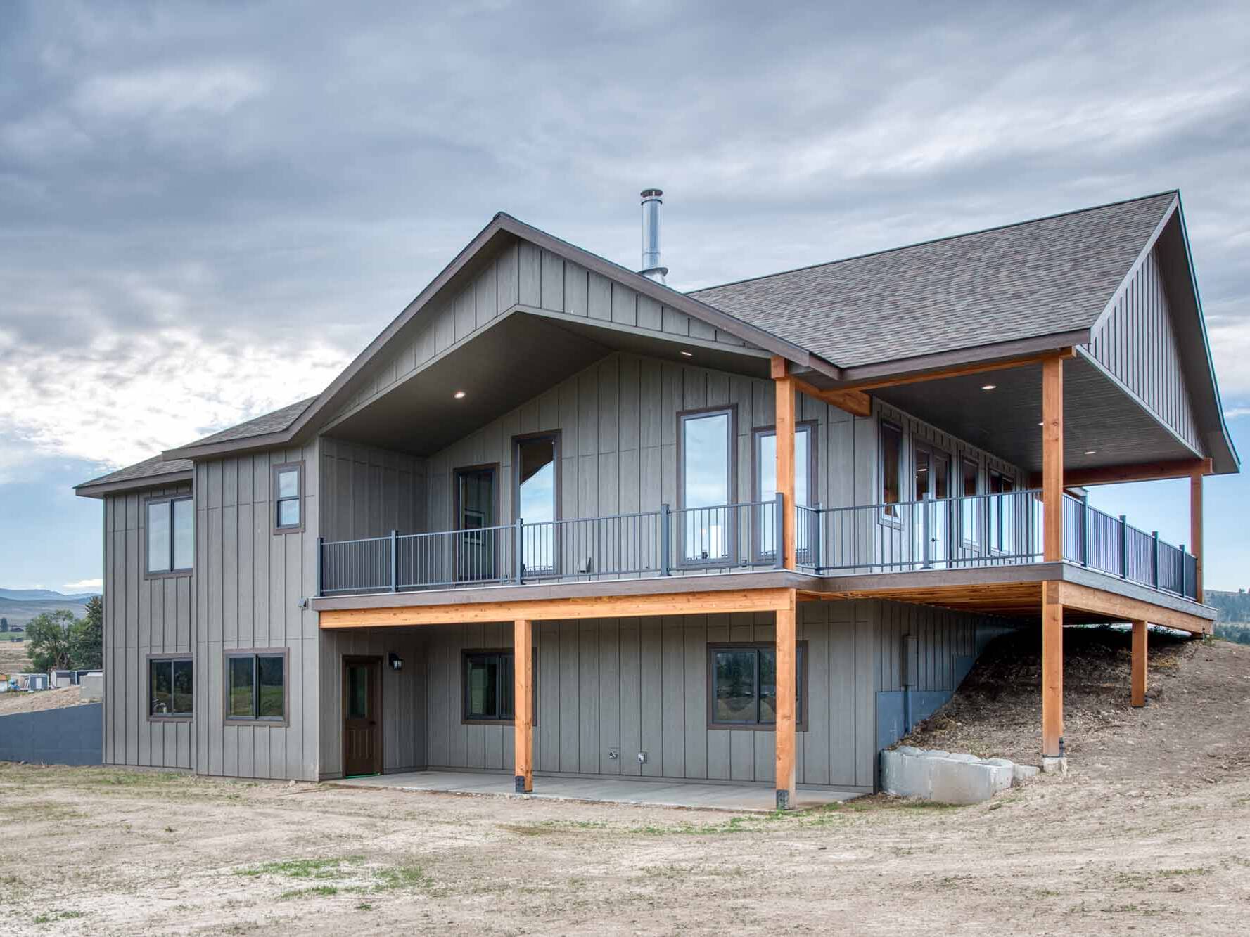 Exterior of a custom home with a covered wrap around porch and timber framing built by Big Sky Builders in Stevensville, MT