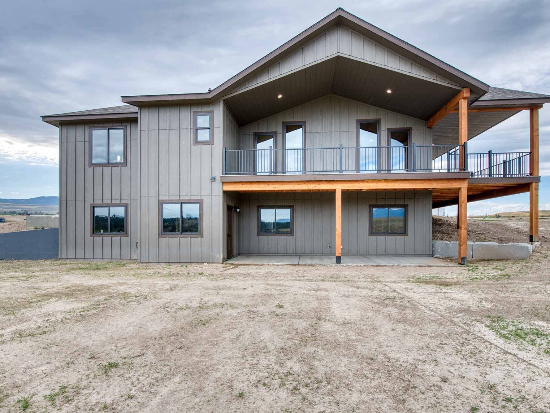 Exterior of a custom home with a covered wrap around porch and timber framing built by Big Sky Builders in Stevensville, MT