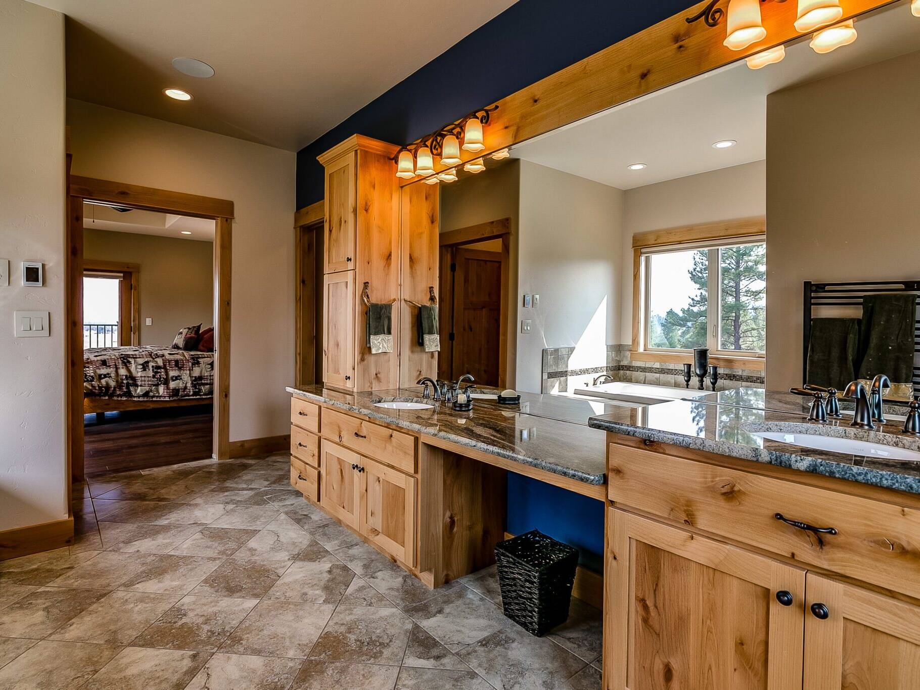 Master bathroom with heated tile floor, granite countertops, large vanity mirror and drop-in tub inside a custom home built by Big Sky Builders near Stevensville, Montana