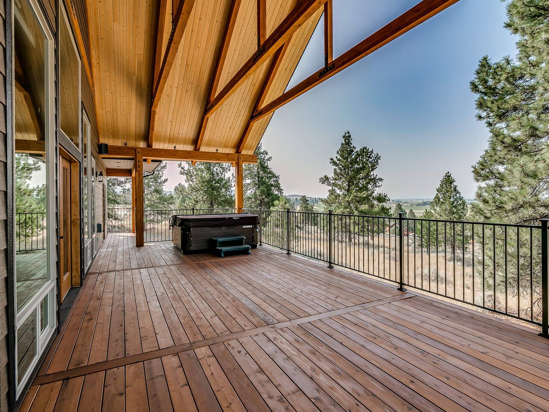 Covered redwood deck with timber trusses at a custom home built by Big Sky Builders near Stevensville, Montana